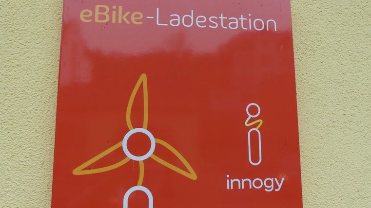 A red sign with the inscription "eBike charging station". It displays a symbol for a wind turbine and the logo of innogy.