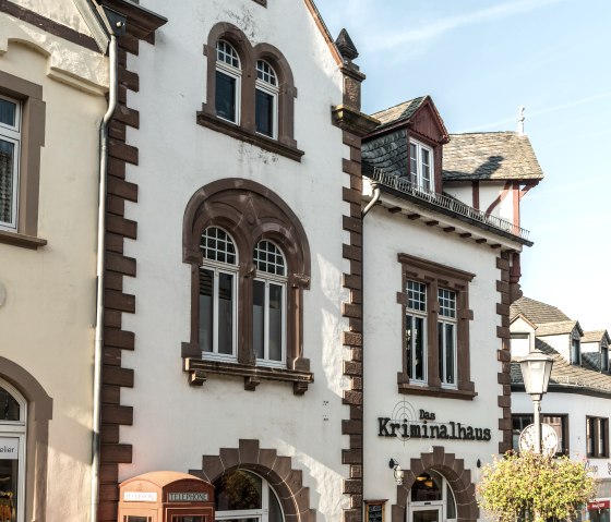 Historisches Geb&auml;ude in Hillesheim mit roter Telefonzelle und Schild 'Das Kriminalhaus'. Sonniger Tag, blauer Himmel., &copy; Eifel Tourismus GmbH, Dominik Ketz