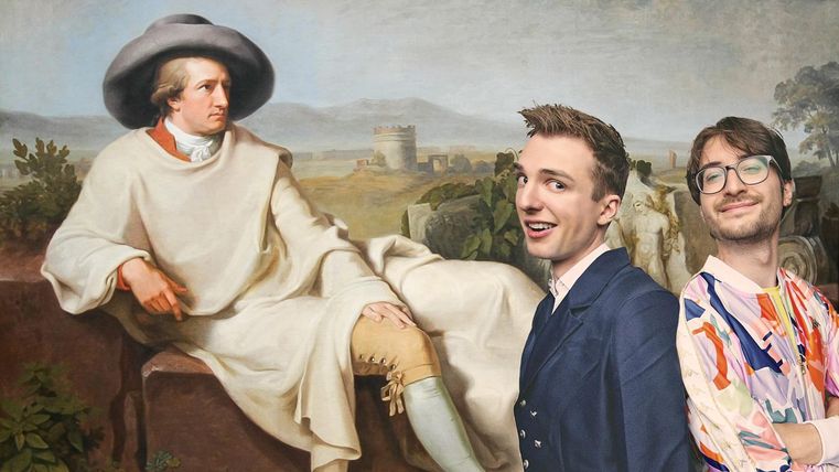 Twee jonge mannen voor een schilderij waar een man op een steen zit. Op de achtergrond is een ronde toren van een kasteel.
