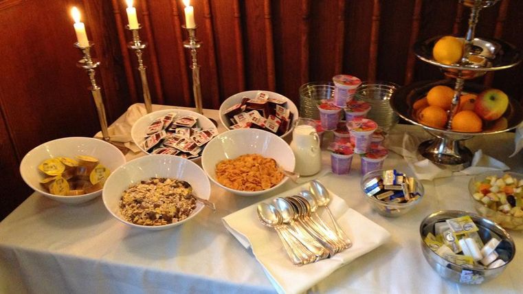 Ein dekorierter Tisch mit verschiedenen Frühstücksoptionen, darunter Müsli, Obst und Joghurt. Kerzen und Besteck verleihen dem Arrangement eine einladende Atmosphäre.